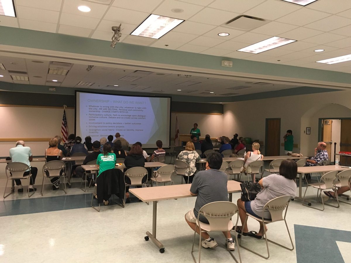 Deltona residents attending a Be the Change civic engagement meeting, seated at tables listening to a presentation on community ownership and getting involved