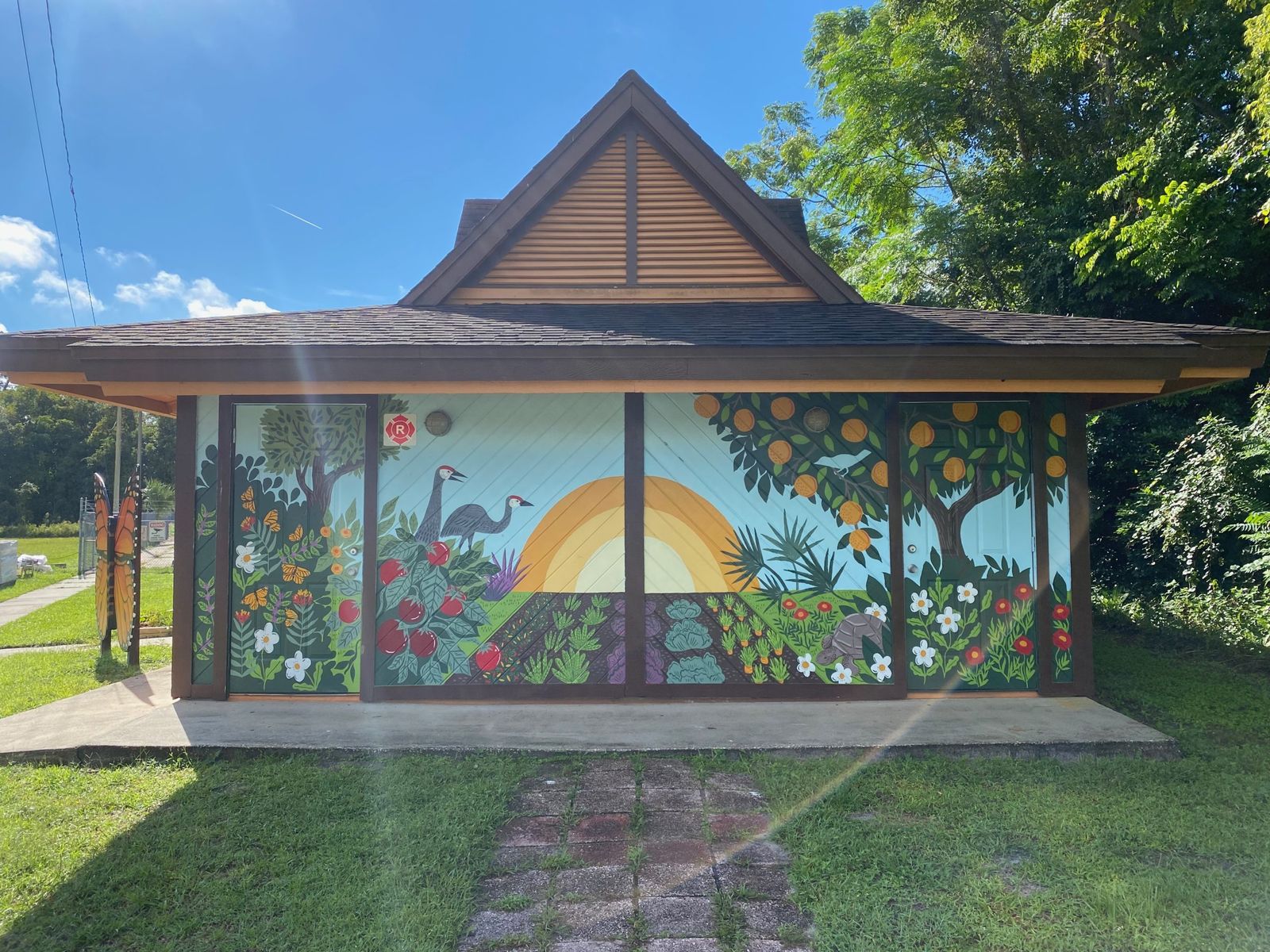 Hand-painted mural of a Florida sunrise, sandhill cranes, and a vegetable garden on the pavilion at Deltona Community Gardens