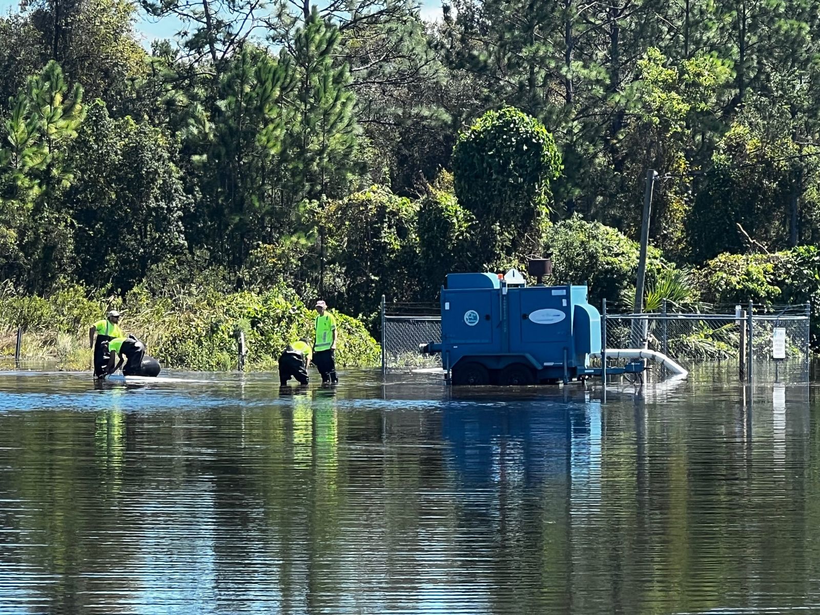 Volunteers wading through Hurricane Ian floodwaters to check on a neighborhood pump station